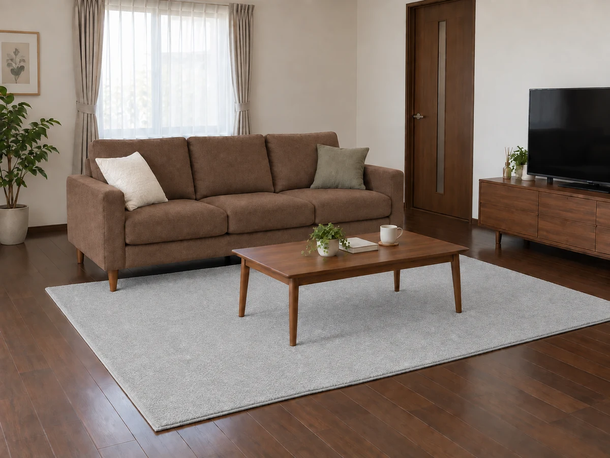 濃い茶色の床にブラウンソファとライトグレーの無地ラグを合わせた配色例